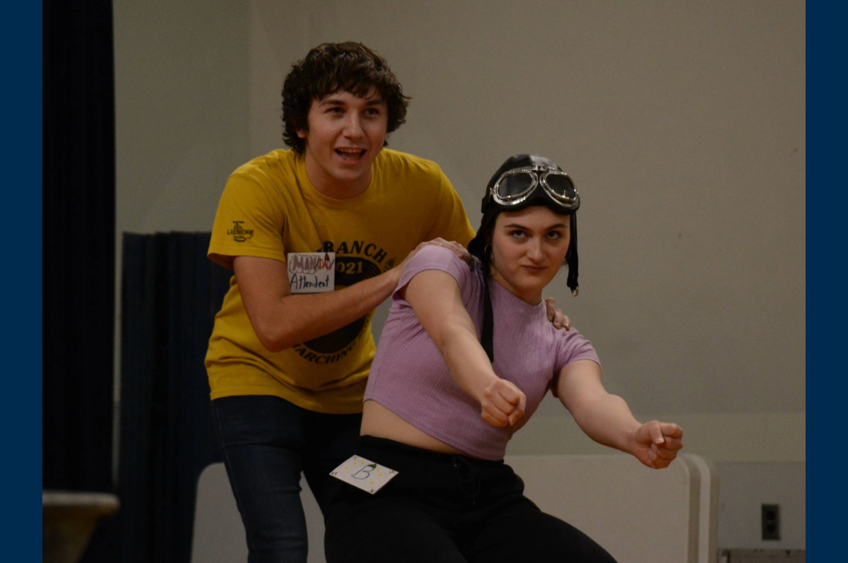 student in flight helmet with student in yellow shirt